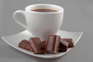  chocolate lies on a saucer with black coffee on a grey background