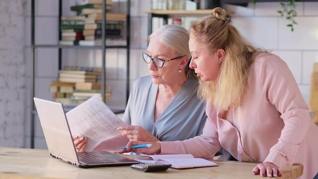 Woman teaching senior mother to use internet at home. Senior woman with her daughter looking at modern gadget indoors. close up view. Slow motion nvideo. stock footage