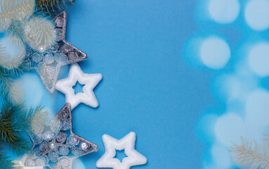 Fototapeta na wymiar christmas background with bokeh and stars on a blue background with fir branches, delicate christmas card