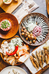 a large clay plate with a national Slavic delicacy - thinly sliced lard with spices on the table among other dishes. Concept for restaurant or menu