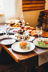 traditional russian herring salad under a fur coat and olives on a wooden table next to other festive dishes