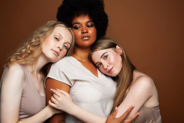 Fototapeta premium young pretty african and caucasian women posing cheerful together on brown background, lifestyle diverse nationality people concept