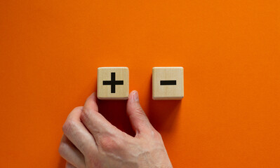 Plus or minus. Businessman holds a cubes with plus icon. Wooden cube with minus icon. Beautiful...