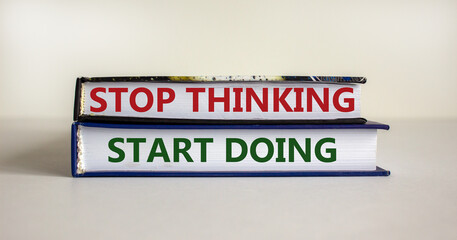 Time to start doing. Books with text 'stop thinking start doing' on beautiful white table. White background. Business, motivation and start doing concept, copy space.