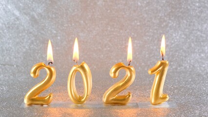 burning golden New Year candles 2021 on a silver background. modern concept.