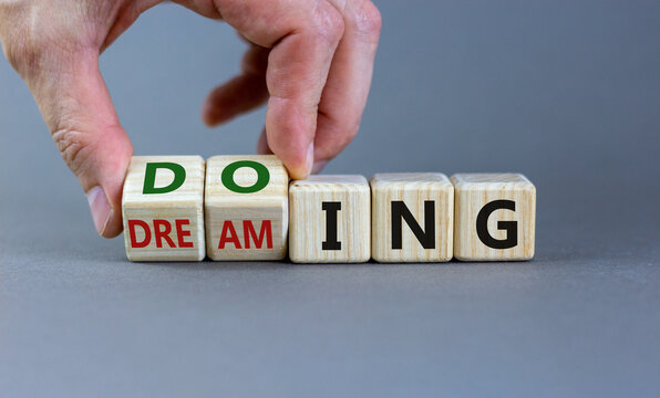Time to start doing. Hand turns cubes and changes the word 'dreaming' to 'doing'. Beautiful grey background. Business, motivational and start doing concept. Copy space.