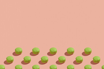 Green macaroons with shadows on colored background. Trendy minimal pattern with copy space. French cookies macarons on a pink pastel background. Delicious french dessert. Creative modern background
