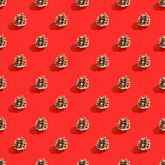 Pine cones on a bright red background. Christmas decorations. Minimal composition seamless pattern background. Christmas and New year concept. Top view, flat lay