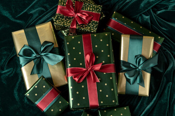 Fototapeta na wymiar Mountain of Christmas gifts wrapped in gold paper with tidewater green satin ribbons. Happy New Year.