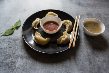 Close up of   Popular snacks  momos on a black plate along with condiments with use of selective focus.