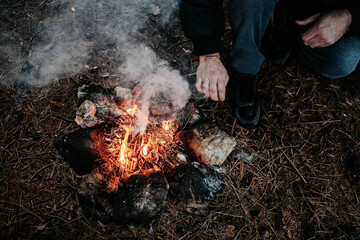 Close-up of man making bonfire. Outdoors grainy photo, top view
