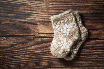 Two wool baby Christmas socks decor on the old wooden planks background