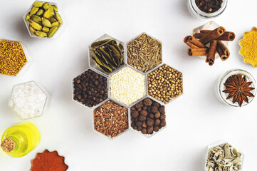 Spices in hexagonal jars on a white background