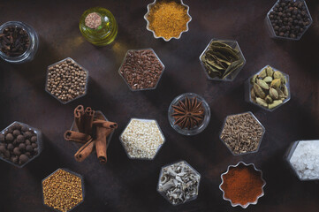 Spices in hexagonal jars appear on a metal rusty baking sheet