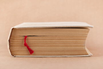 Thick book with red rope bookmark lying on brown paper background. Front view.Selective focus.Concept of reading,learning.