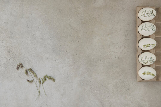 Painted Easter eggs and grass flowers on a gray background
