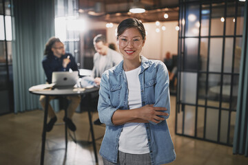 Asian businesswoman smiling with colleagues working behind