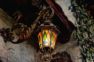 Colored vintage lantern made of stained glass and metal frame. Multi-colored colorful glass like a mosaic, calm subdued light in the evening at dusk