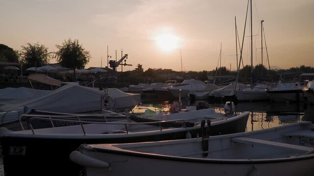Manerba del Garda Marina on Garda Lake, Italy. Bounded Boats, Sailing Boats and Yachts Under Sunset Sulight, Slow Motion