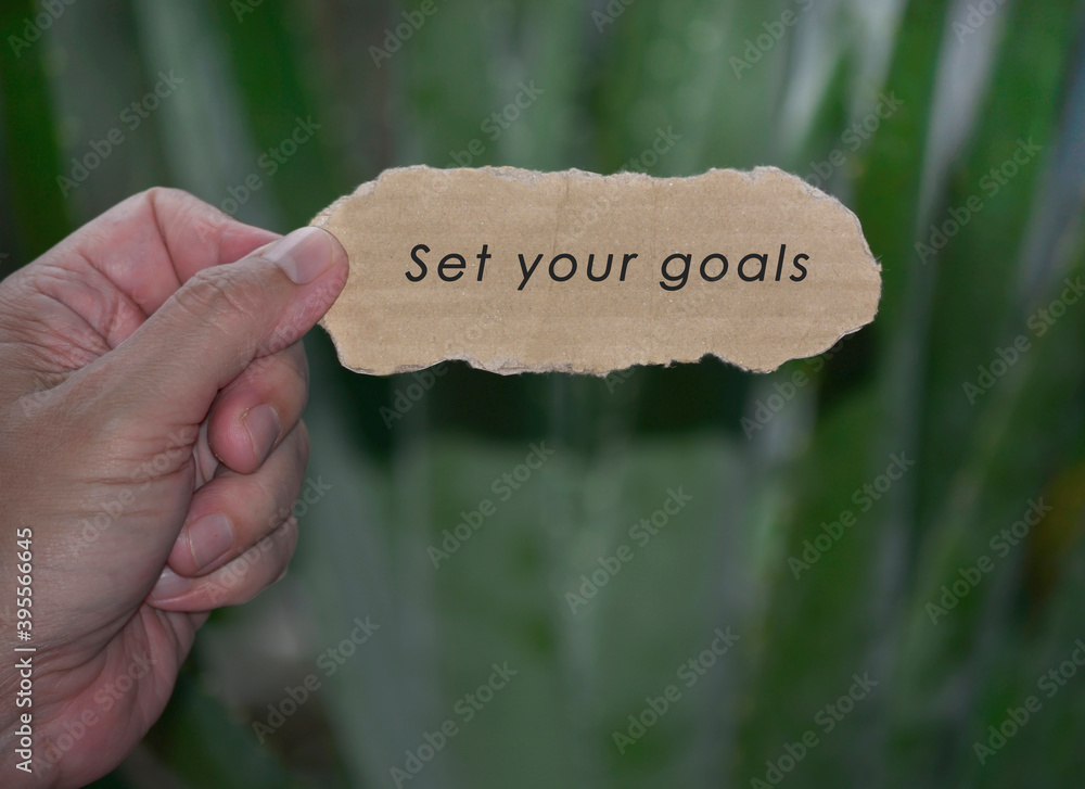 Wall mural hands holding torn paper with motivational quote and blurred green background