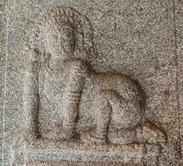 Hampi, Karnataka, India - November 4, 2013: Virupaksha Temple complex. Closeup of gray stone mural sculpture of woman on all fours.