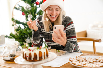 Positive girl in christmas santa hat eating cake
