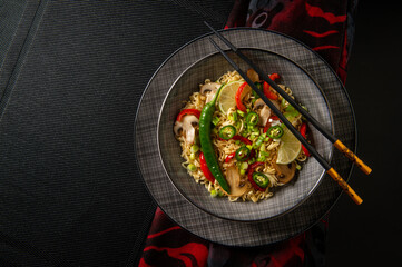 Asian noodles. Noodles with mushrooms and vegetables. Food sticks. Plate with noodles on a dark background.