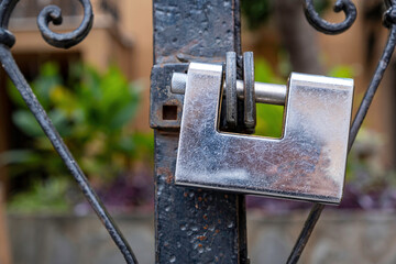 Heavy metal padlock closeup on a brown color entrance gate.