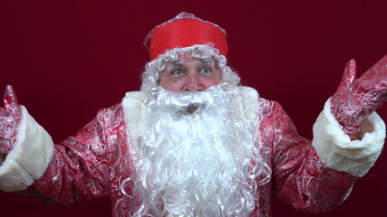 Russian santa claus on a red background spread his hands in which there are no gifts and shrugged his shoulders