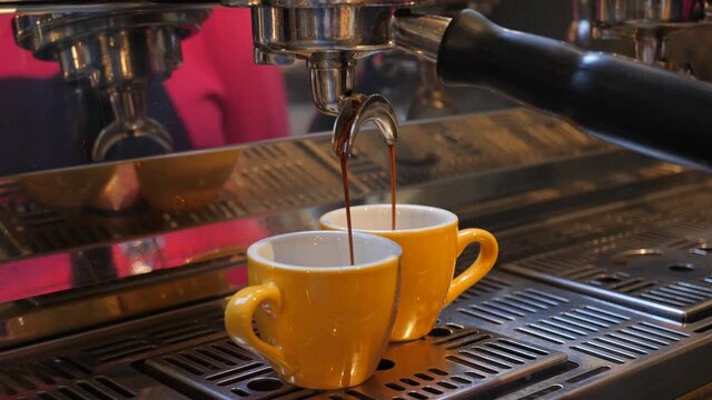 Barista making coffee two small portion yellow cups on expresso maching in a bar