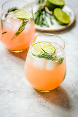 sliced lime, rosemary, plate and juice in glass on stone table background