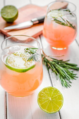 glass of fresh juice with lime, rosemary and knife on wooden background