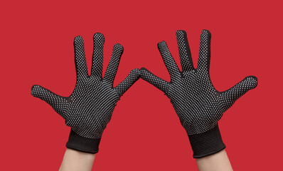 Hands in black coated natural protective gloves. On a red background.