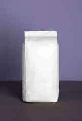 Small blank bulky white package with product on a purple-lilac background . Ready for shipping, delivery and sale.