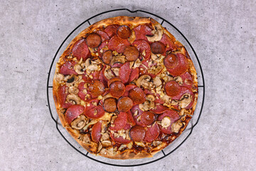 Top view of freshly baked pizza with salami and sujuk sausage slizes, mushrooms and mozzarella...