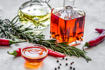 oil in carafe with spices, olives and chili on stone background