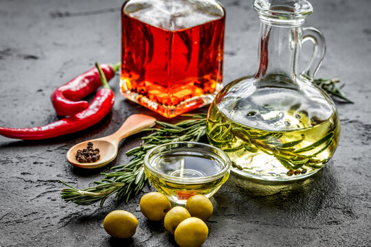 Bottles with chili and olive oils and herbs on stone background
