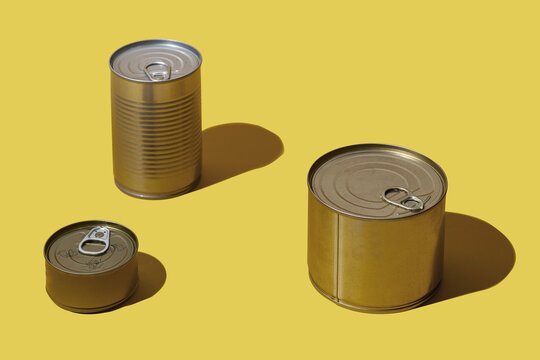 Three different tins on a yellow surface