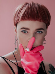 Portrait of a girl with a short haircut in rubber pink gloves on a pink background