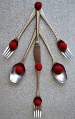 Christmas greeting for restaurants: Christmas tree consisting of steel spoons, forks and knives with raspberries as balls on a shiny silver background