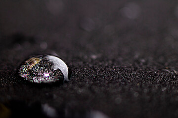 A drop of water on a black surface. Side view with place for text. Spa concept. Selective focus.