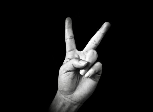 Sign Of Peace Of A Woman Hand In A Black Background