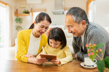 タブレット学習をする孫を見守る祖父母