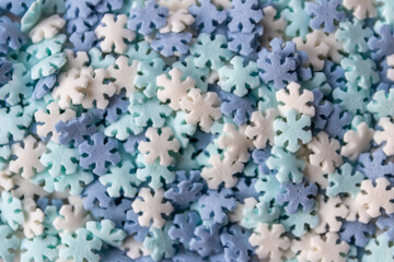 Christmas snowflake sprinkles in blue and white as delicious background and sweet candy topping for birthday cakes and Christmas decoration in close-up view and high angle view in advent time