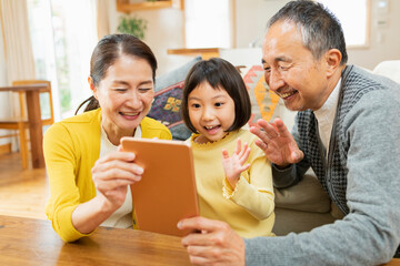 タブレット学習をする孫を見守る祖父母