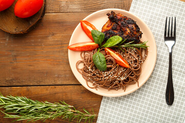 Plate of soba with chicken tomatoes and spinach on a linen napkin next to a fork and a sprig of rosemary and tomatoes.