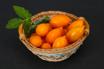 Yellow tomato heap in the wooden bowl