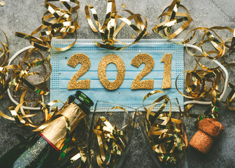 New Years Eve celebration concept background.Medical mask with the numbers 2021 and Champagne bottle with glasses .Covid-19 New Year concept