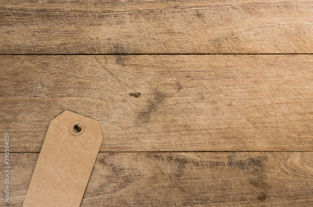Poster top view of cardboard tag with a hole on a wooden table with copy space