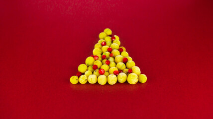 Obraz premium christmas tree made from gooseberries and cranberries on red background